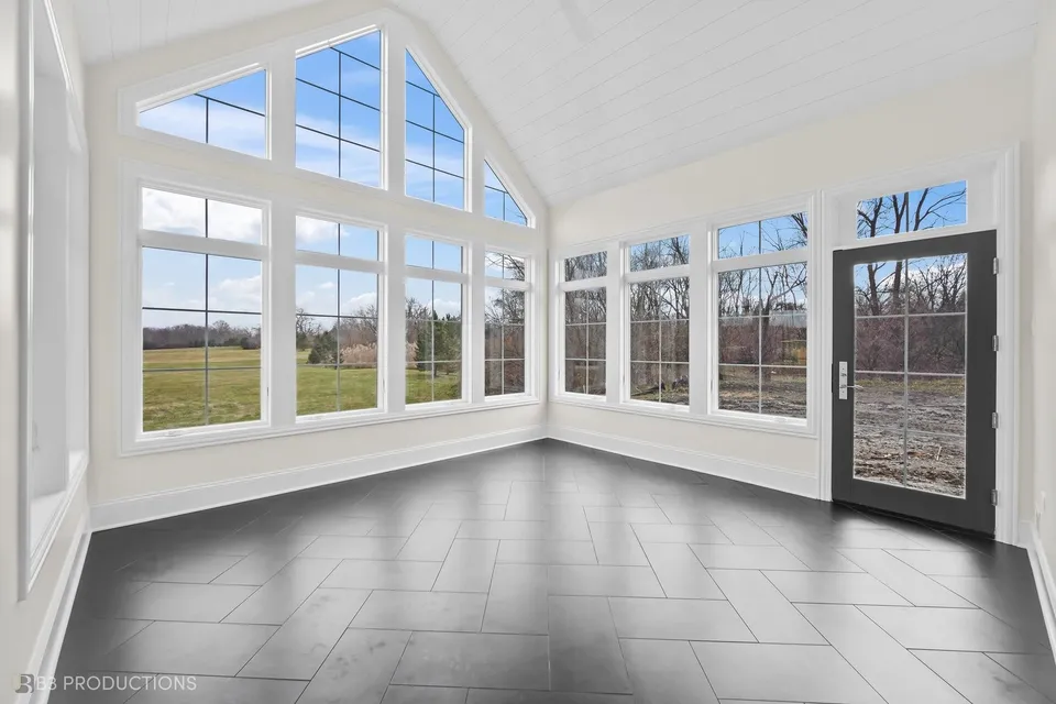 Sunroom with a vaulted shiplap ceiling, a gable window rising to the peak, and a slate tile floor
