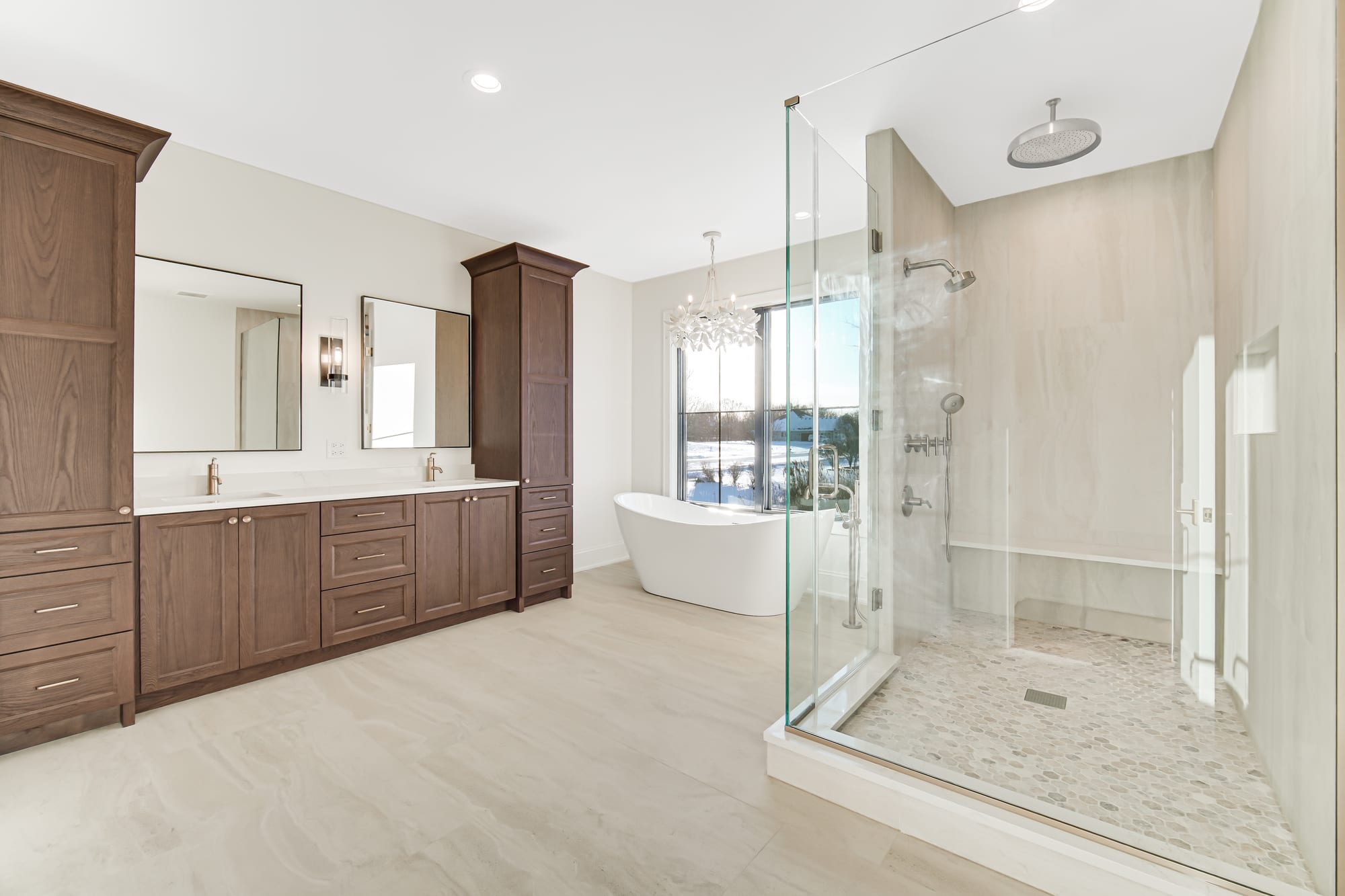 Primary bathroom with a freestanding soaking tub, walnut double vanities, and a glass shower