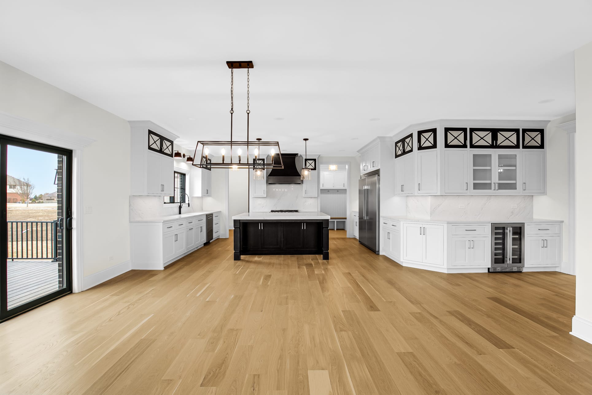 Open kitchen and dining room with a black island, white cabinetry, and a built-in wine fridge