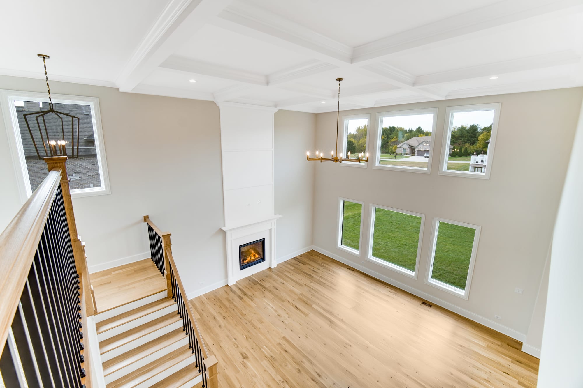 Living room with a coffered ceiling and a fireplace, seen from the open oak staircase